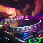 Close-up of a DJ's hands on mixing console at a vibrant party in Utrecht.